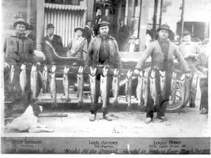 old black and white photo of men holding a stringer of fish they caught